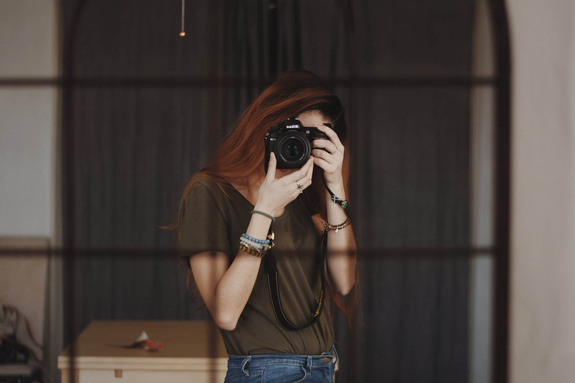 a woman taking photo of herself in the mirror using a dslr camera